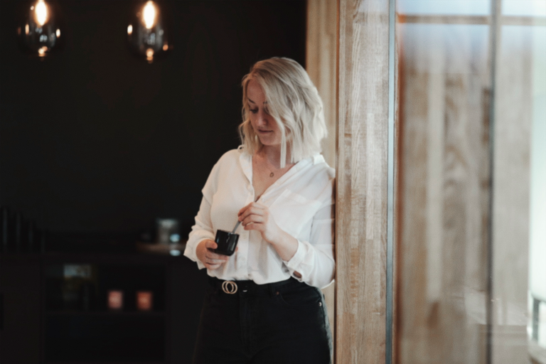 Frau in weißer Bluse mit Smartphone in einem Café