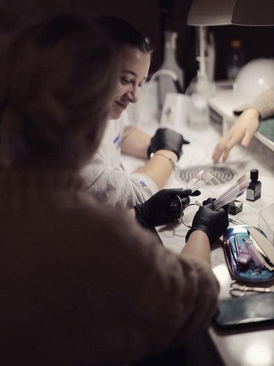 Nageldesignerin arbeitet an einer Kundin