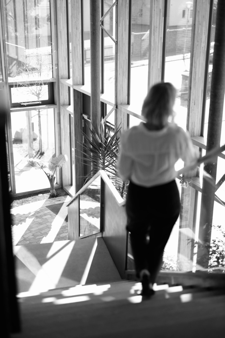 Schwarz-Weiß: Frau geht eine lichtdurchflutete Treppe hinunter